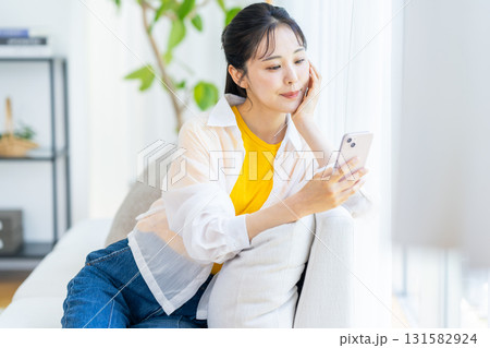 部屋でスマホを操作する女性 131582924
