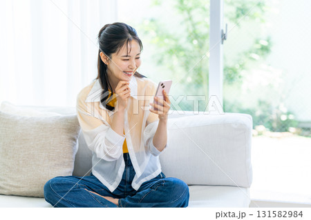 部屋でスマホを操作する女性 131582984