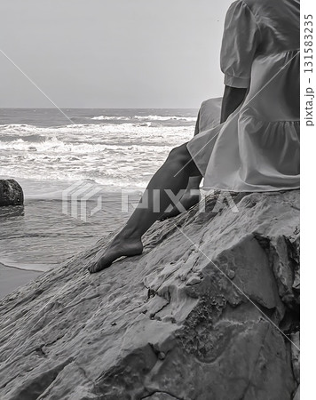 Woman sitting on rock watching wild sea waves. Woman sitting on rock watching wild sea waves. 131583235