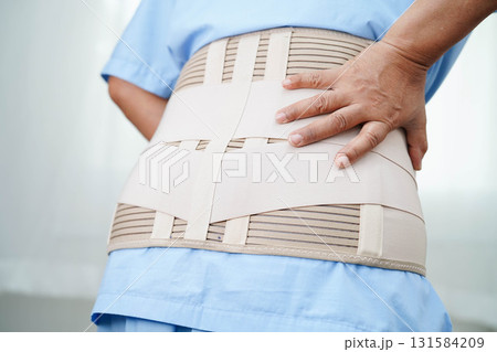 Asian senior pain back wearing elastic support belt with walker. 131584209
