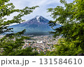 Scenic view of Mount Fuji overlooking Fujiyoshida City in springtime framed with lush green foliage in foreground 131584610