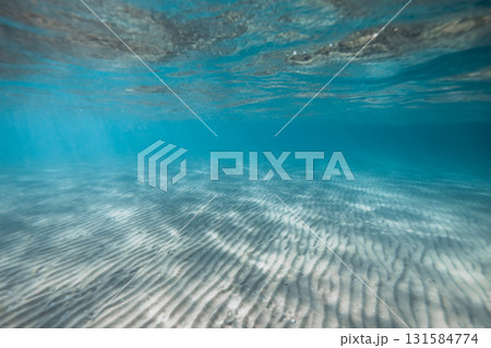 Scenic underwater view of sandy seabed with sun rays shining through clear blue water 131584774