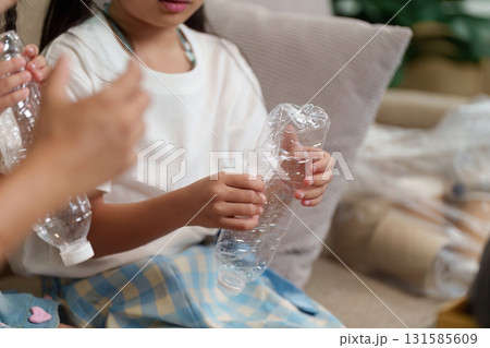 Sustainability and Child Education. Children engage in recycling practices by preparing plastic bottles for disposal. 131585609