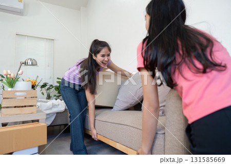 Furniture Moving and Strength. A couple lifts a sofa together, showcasing teamwork in their moving process. Furniture Moving and Strength. A couple lifts a sofa together, showcasing teamwork in their moving process. 131585669
