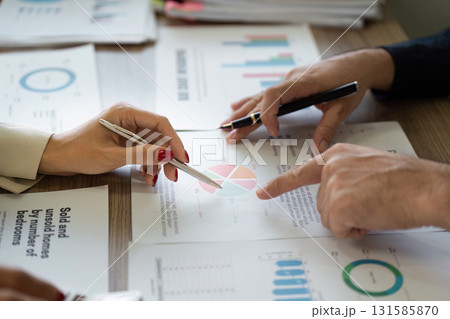 Collaborative financial analysis with team members reviewing charts and reports. 131585870
