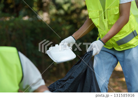 Sustainable Waste Collection. A volunteer gathers food containers during a community cleanup. Sustainable Waste Collection. A volunteer gathers food containers during a community cleanup. 131585916