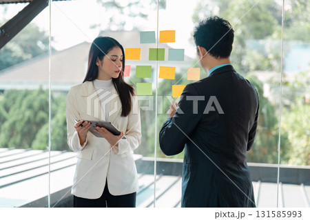 Business team brainstorming with sticky notes in a modern office, discussing project strategies Business team brainstorming with sticky notes in a modern office, discussing project strategies 131585993