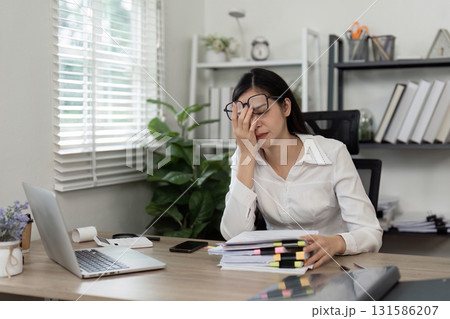 Stressed accountant overwhelmed by paperwork in a modern office setting. Stressed accountant overwhelmed by paperwork in a modern office setting. 131586207