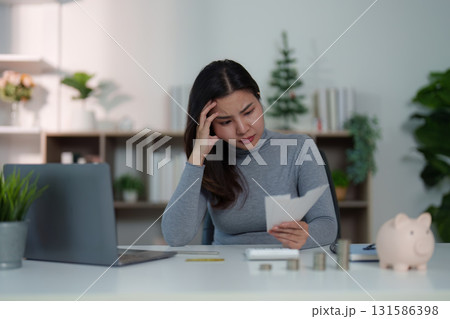 Financial Stress. Woman looking worried while reviewing expenses and savings. 131586398