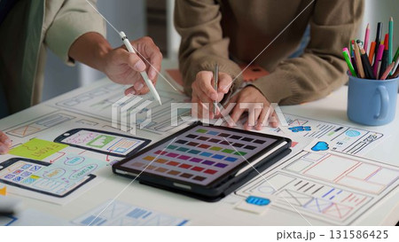 User Interface Design. Team discussing digital mockups and color palettes on a tablet. User Interface Design. Team discussing digital mockups and color palettes on a tablet. 131586425