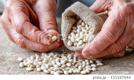 Elderly hands holding white beans from burlap sack, symbolizing longevity, nutrition, tradition, and healthy eating, with rustic background and natural light for warm feeling Elderly hands holding white beans from burlap sack, symbolizing longevity, nutrition, tradition, and healthy eating, with rustic background and natural light for warm feeling 131587044