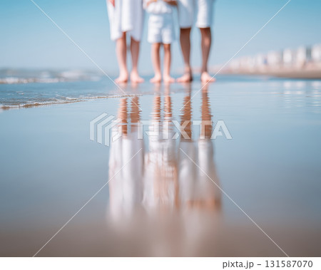 Family feet and legs standing on sandy beach reflected in wet sand wearing white clothing summer day relaxed mood ocean waves blue sky vacation atmosphere 131587070