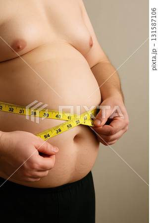 Overweight belly with measuring tape close up adult male bare torso obesity health body fat skin waist unhealthy measurement human lifestyle overweight diet weight loss fitness healthcare abdomen Overweight belly with measuring tape close up adult male bare torso obesity health body fat skin waist unhealthy measurement human lifestyle overweight diet weight loss fitness healthcare abdomen 131587106