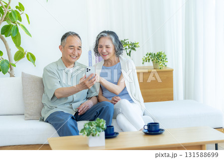 リビングでスマホを見るシニア夫婦 131588699