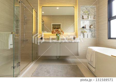 Contemporary master bathroom features a dark vanity cabinet fitted with rectangular his and hers sink and modern wall mount faucets also modern tub by the window. 131589571