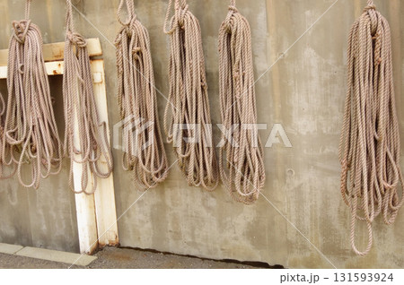 海辺の倉庫の壁に、様々な種類のロープの束がぶら下がっている。 131593924