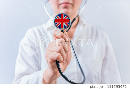 Female doctor holding stethoscope with United Kingdom flag. National health system of United Kingdom 131595471