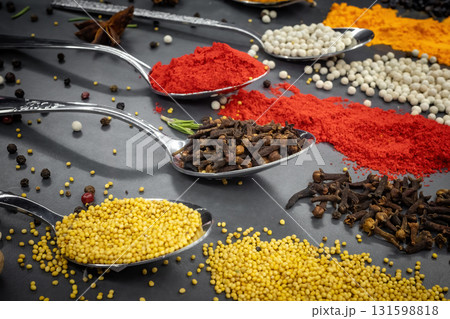 Collection of spices are spread out on a table. The spices include cumin, paprika, and turmeric Collection of spices are spread out on a table. The spices include cumin, paprika, and turmeric 131598818