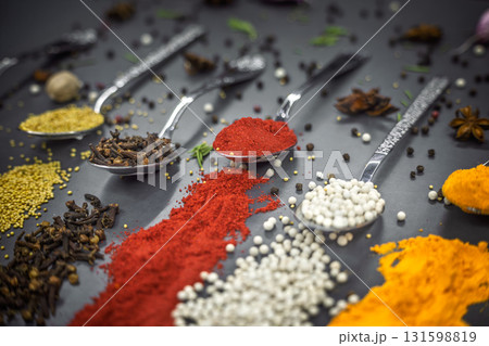 Collection of spices are spread out on a table. The spices include cumin, paprika, and turmeric Collection of spices are spread out on a table. The spices include cumin, paprika, and turmeric 131598819