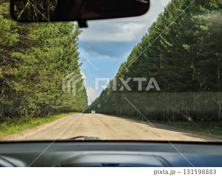 Gravel forest road through pine trees, car interior view, summer day, horizontal frame Gravel forest road through pine trees, car interior view, summer day, horizontal frame 131598883