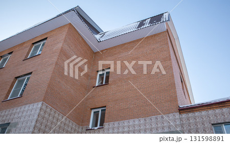 Brick residential building with tiled roof and snow, blue sky, horizontal low angle, worm eye view, low angle Brick residential building with tiled roof and snow, blue sky, horizontal low angle, worm eye view, low angle 131598891