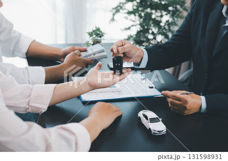 Customer receiving car key from dealer after signing contract, successful auto purchase and finance agreement at office desk, concept of vehicle loan, leasing, insurance or ownership. vehicle loan. 131598931