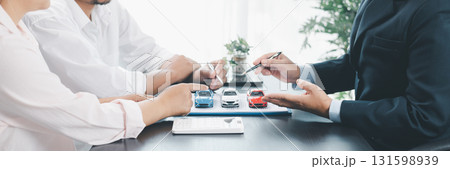 Panorama view of car loan agreement signing with dealer presenting vehicle model, customer using calculator at office desk, concept of auto finance, leasing, insurance and business contract. Panorama view of car loan agreement signing with dealer presenting vehicle model, customer using calculator at office desk, concept of auto finance, leasing, insurance and business contract. 131598939