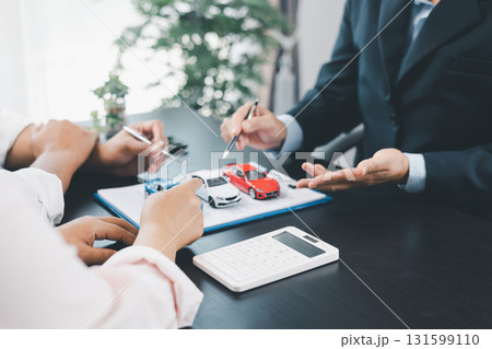 Customer signing car loan contract with dealer showing vehicle model, concept of auto finance, leasing, insurance or purchase agreement, business negotiation and financial planning. auto finance. Customer signing car loan contract with dealer showing vehicle model, concept of auto finance, leasing, insurance or purchase agreement, business negotiation and financial planning. auto finance. 131599110