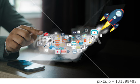 Startup rocket launch, fast growth, digital advertising success. Business hand at a laptop triggers flying icons, representing SEO, PPC, content, email, data analytics. 131599485