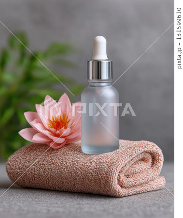 Glass dropper bottle on towel with pink flower for skincare 131599610
