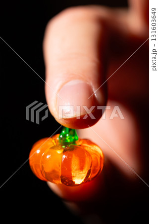 Finger Holds Small Glass Pumpkin for Festive Halloween Postcard Design Finger Holds Small Glass Pumpkin for Festive Halloween Postcard Design 131603649