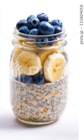 Glass jar filled with overnight oats, almond milk, chia seeds, and topped with blueberries and banana slices - isolated on white background. Minimal aesthetic, healthy breakfast, transparent 131604059
