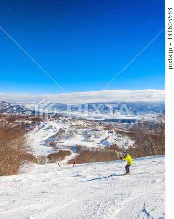 快晴のスキー場で絶景を見ながら非圧雪コースを滑走するスキーヤー (新潟県、斑尾高原) 快晴のスキー場で絶景を見ながら非圧雪コースを滑走するスキーヤー (新潟県、斑尾高原) 131605583
