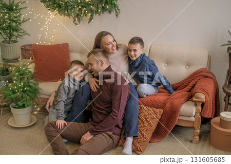 A young happy family with two sons on the sofa of the living room decorated for Christmas and New year. On the eve of the holidays. 131605685