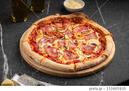 Pizza with ham and mushrooms on black stone table 131605920