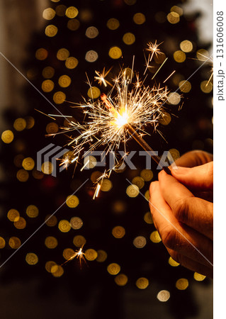 festive bright sparkler in male hands on the background of a christmas tree. closeup. festive bright sparkler in male hands on the background of a christmas tree. closeup. 131606008