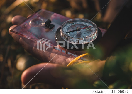 man holding compass in forest during sunny day while exploring natural surroundings. closeup. man holding compass in forest during sunny day while exploring natural surroundings. closeup. 131606037