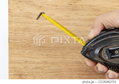 Measuring tape yellow tape wood surface hand tool construction carpentry DIY workshop precision measuring tape extends across wood with hand holding tool, careful carpentry and DIY work evoke Measuring tape yellow tape wood surface hand tool construction carpentry DIY workshop precision measuring tape extends across wood with hand holding tool, careful carpentry and DIY work evoke 131606254