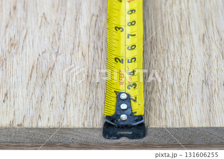 Measuring tape yellow metal wood closeup tool metric imperial inch scale snug focus measuring tape against wood board, precise craft mood, workshop vibe, carpentry detail, accuracy and build pride Measuring tape yellow metal wood closeup tool metric imperial inch scale snug focus measuring tape against wood board, precise craft mood, workshop vibe, carpentry detail, accuracy and build pride 131606255