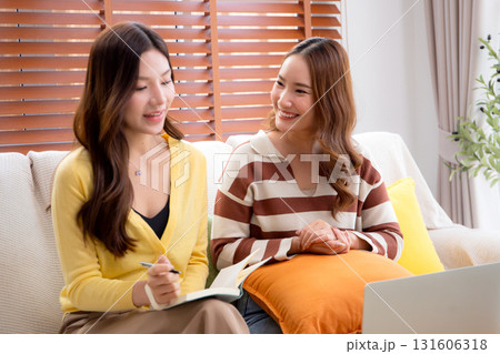 Two asian woman sitting on sofa using laptop computer video call and note taking together. Two asian woman sitting on sofa using laptop computer video call and note taking together. 131606318