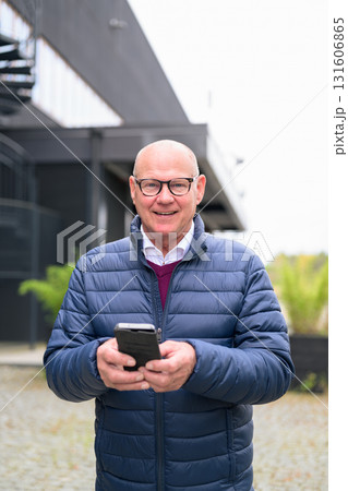 Senior man using his mobile phone in front of a modern building Senior man using his mobile phone in front of a modern building 131606865