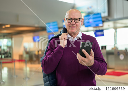 Portrait of happy senior man using mobile phone while standing in airport 131606889