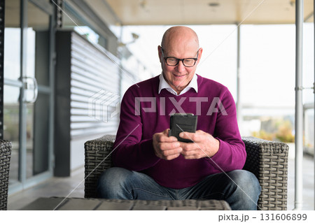 Portrait of a senior man using his mobile phone while sitting outdoors Portrait of a senior man using his mobile phone while sitting outdoors 131606899