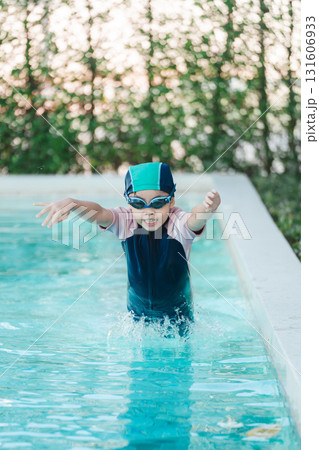 Child in Swim Cap and Goggles Splashing in Pool Water, Capturing Joyful Moment During Summer Swim Lesson in Bright Natural Light Setting 131606933