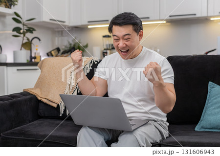 Asian man celebrates work project success on laptop smiles makes victory sign and sends final report Asian man celebrates work project success on laptop smiles makes victory sign and sends final report 131606943