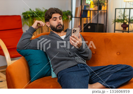 Indian man naps with smartphone wakes to loud alert important message quick look startled reaction 131606959