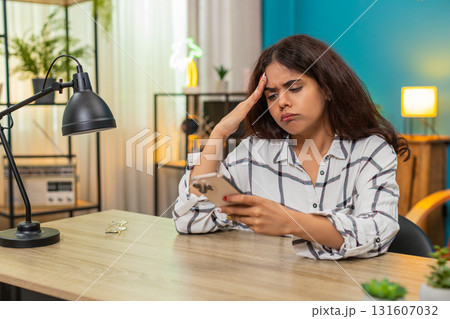 Indian woman upset after bad news on smartphone presses button places phone aside unhappy reaction Indian woman upset after bad news on smartphone presses button places phone aside unhappy reaction 131607032