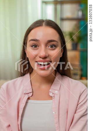 Young woman exclaiming wow with wide eyes huge joyful surprise reaction holding smartphone on sofa Young woman exclaiming wow with wide eyes huge joyful surprise reaction holding smartphone on sofa 131607038