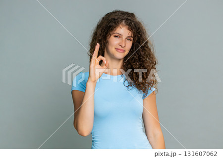 Woman smiling showing OK gesture approval satisfaction positive feedback happy pleased expression Woman smiling showing OK gesture approval satisfaction positive feedback happy pleased expression 131607062