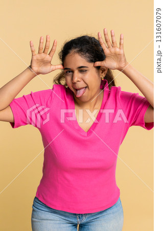 Indian woman playfully sticking out tongue towards camera, expressing joyful teasing personality Indian woman playfully sticking out tongue towards camera, expressing joyful teasing personality 131607079